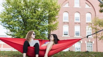 two women chatting in a red hammock