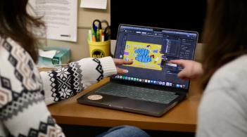 Two graphic designers collaborate on the UVM Bored Awards design project in the student life marketing pit 