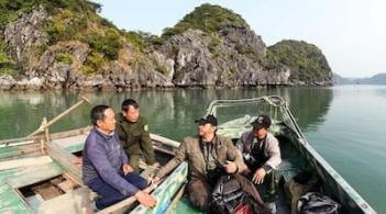 four men in two boats in a tropical bay