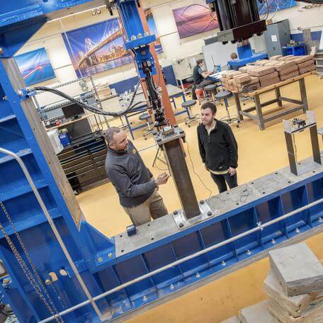student and faculty member inspect large machinery