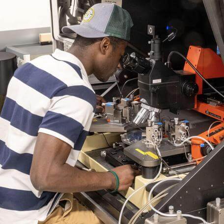 student looks through a microscope at machinery