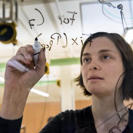 professor writes math on a glass wall