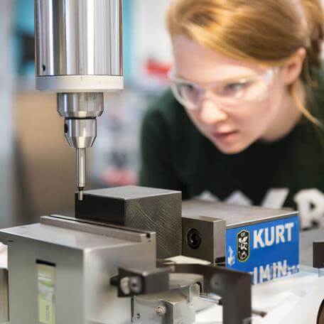 student inspects machinery equipment close up