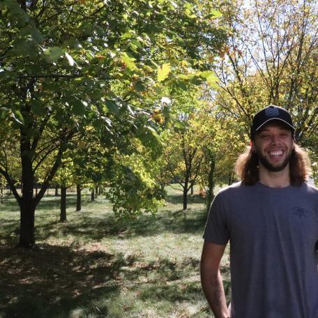Student Ethan Pezzini stands in an apple orchard at the Horticulture Research and Education Center