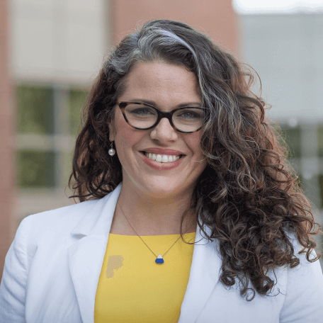 Trisha Shrum standing in front of a UVM building