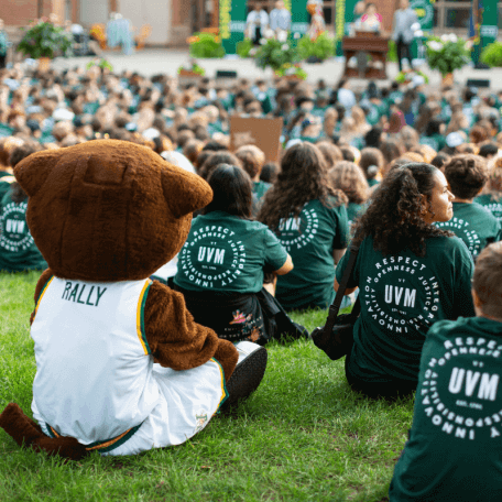 Group of students and a mascot sitting on grass