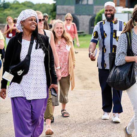 several smiling people walking towards the camera, outdoors