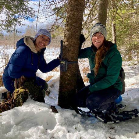 Students placing a camera on a tree at Joe's pond.