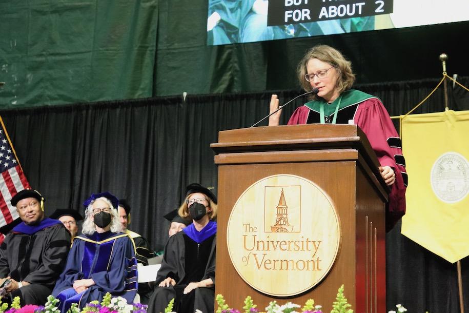 woman dressed in regalia giving commencement speech behind a UVM podium