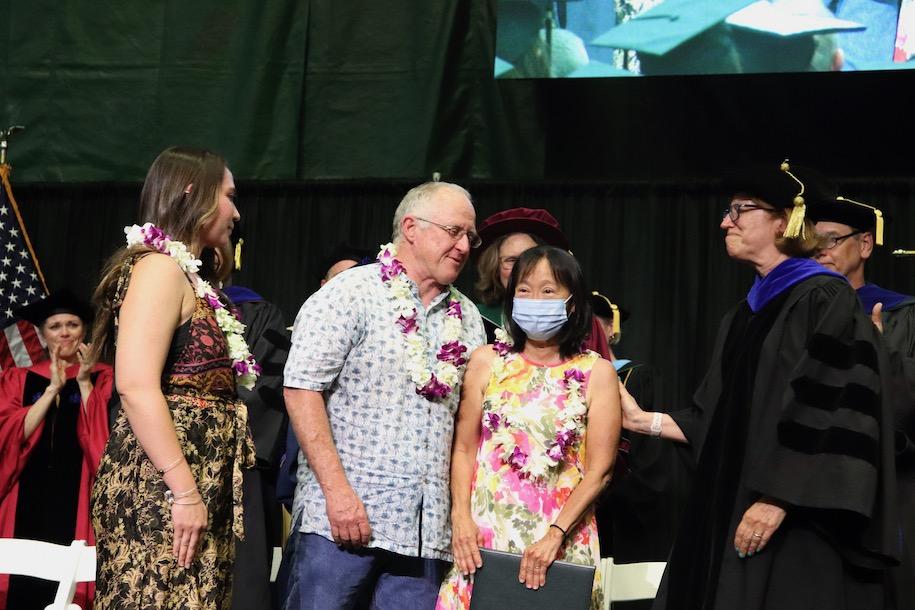three family members gather on commencement platform with dean