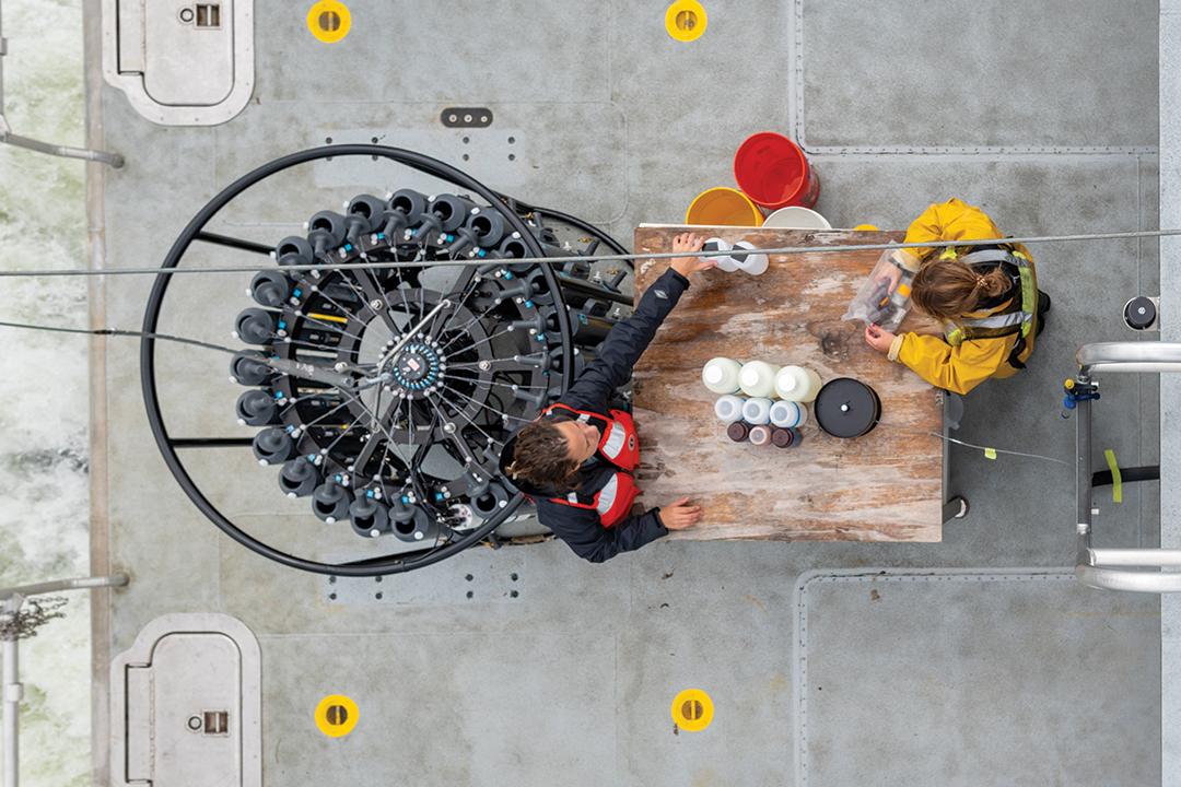 two people are photographed from above working at a wood table surrounded by scientific tools