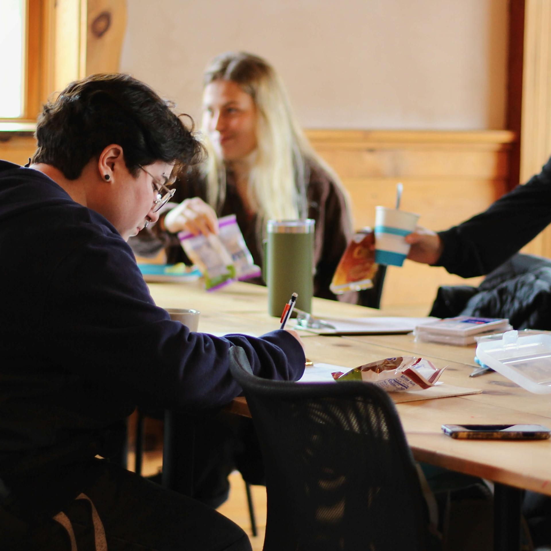 A group of students sit around a table while engaging in discussion at Social Justice Grounding Retreat at the Common Ground retreat center. 