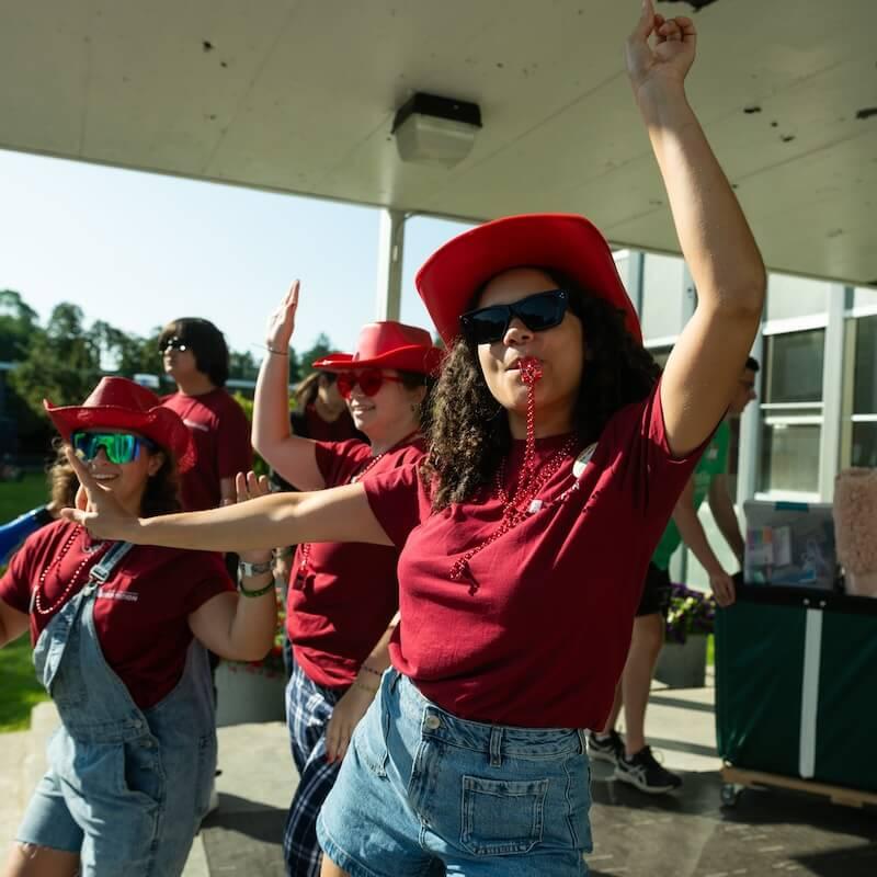 An orientation in a red shirt and cowboy hat playfully directs move-in traffic.