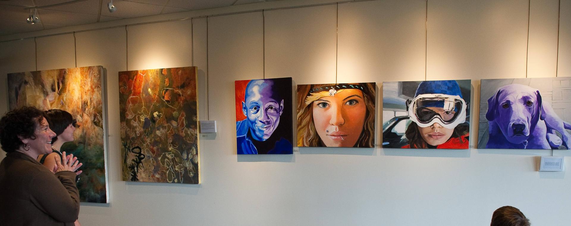 A long wall showcasing submitted artworks in the MASKED Exhibition at UVM