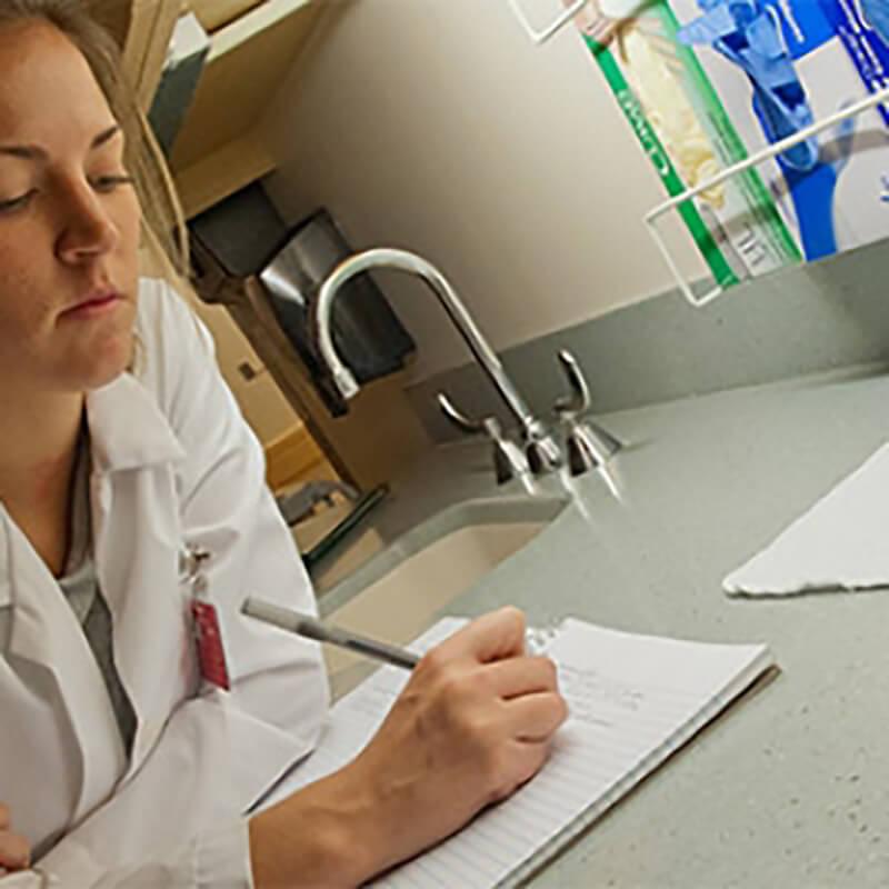 Person writing on a notebook in a research lab
