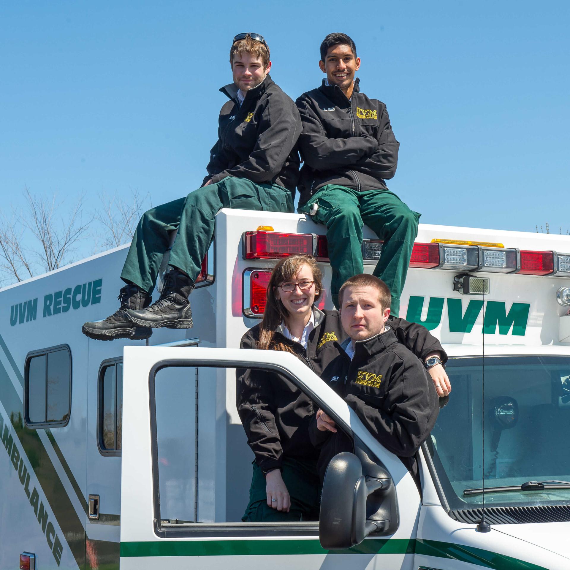 An image of 4 UVM Rescue members sitting atop an ambulance