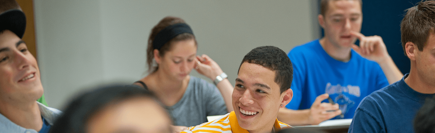 multiple students seated at desks, with happy faces during a class/lecture