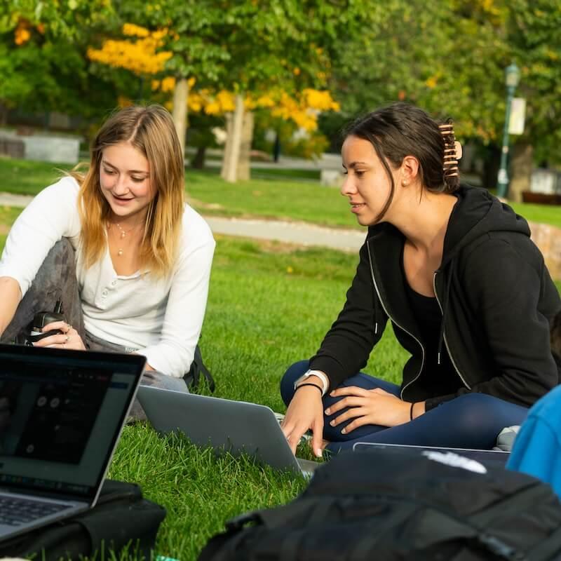 Students sitting outside working on laptops