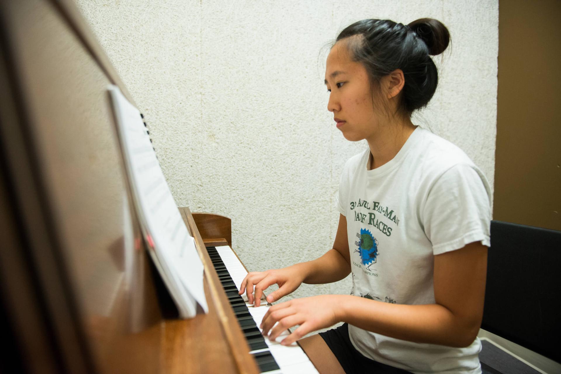 Student playing a piano.