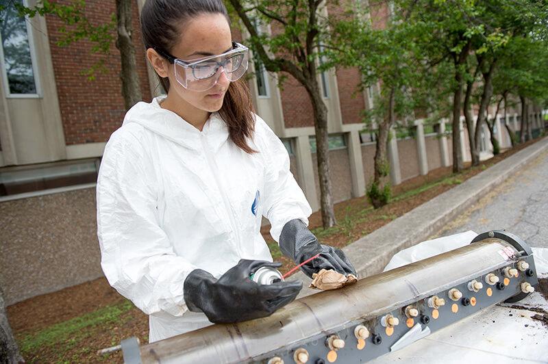 ME student cleaning research device outside of Votey Hall