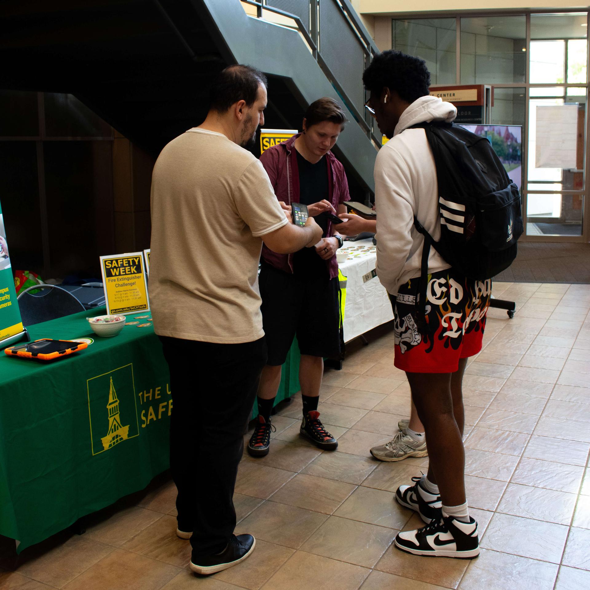 Two Safety & Compliance Staff Members show students the CATSafe App.