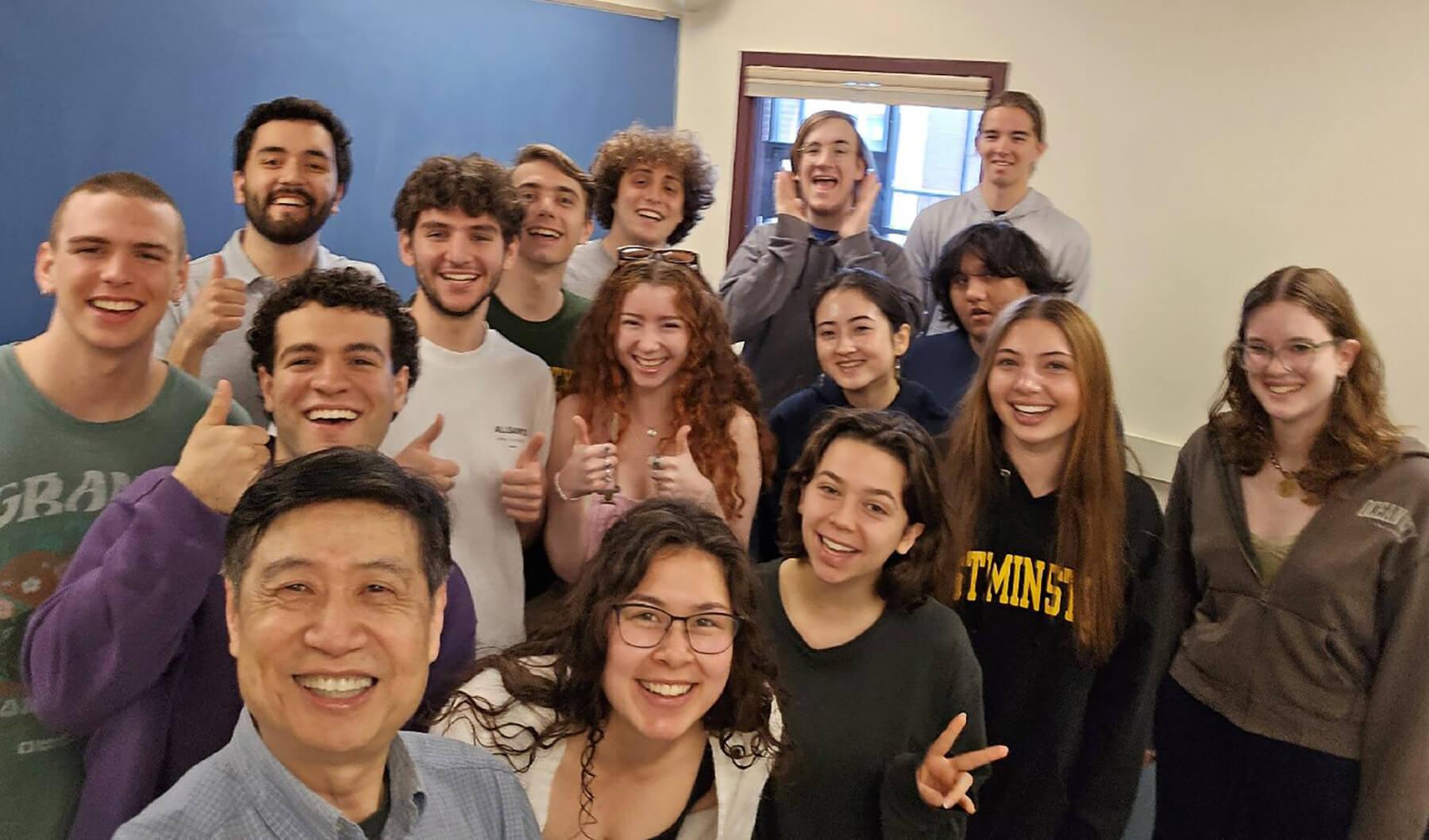 A group of individuals smiling and posing together for a photo inside a classroom setting