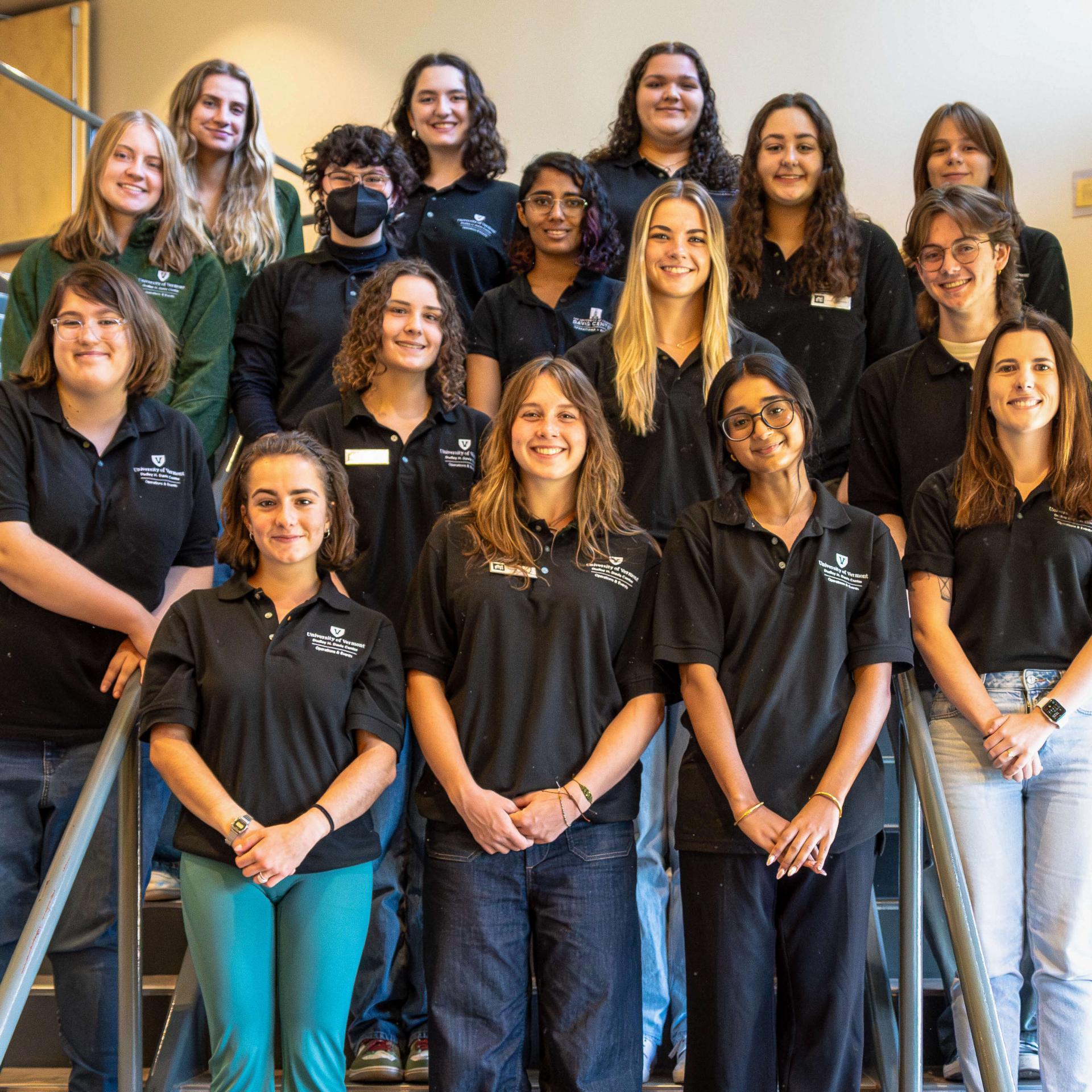A group of student employees pose on the scarlet oak stairway