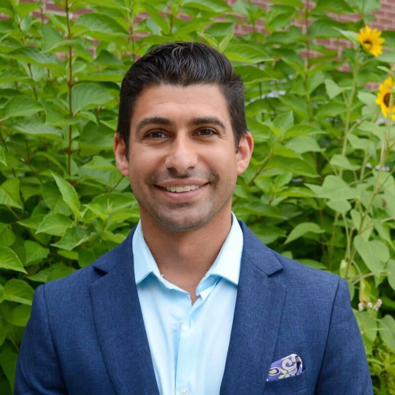 Headshot image of the researcher outdoors, posed in front of green foliage
