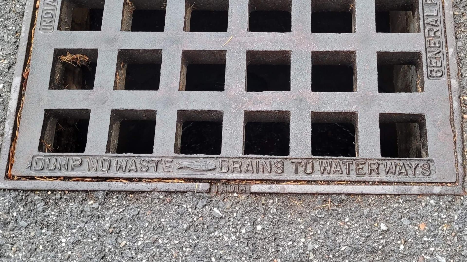A traditional storm drain stamped with Dump No Waste message