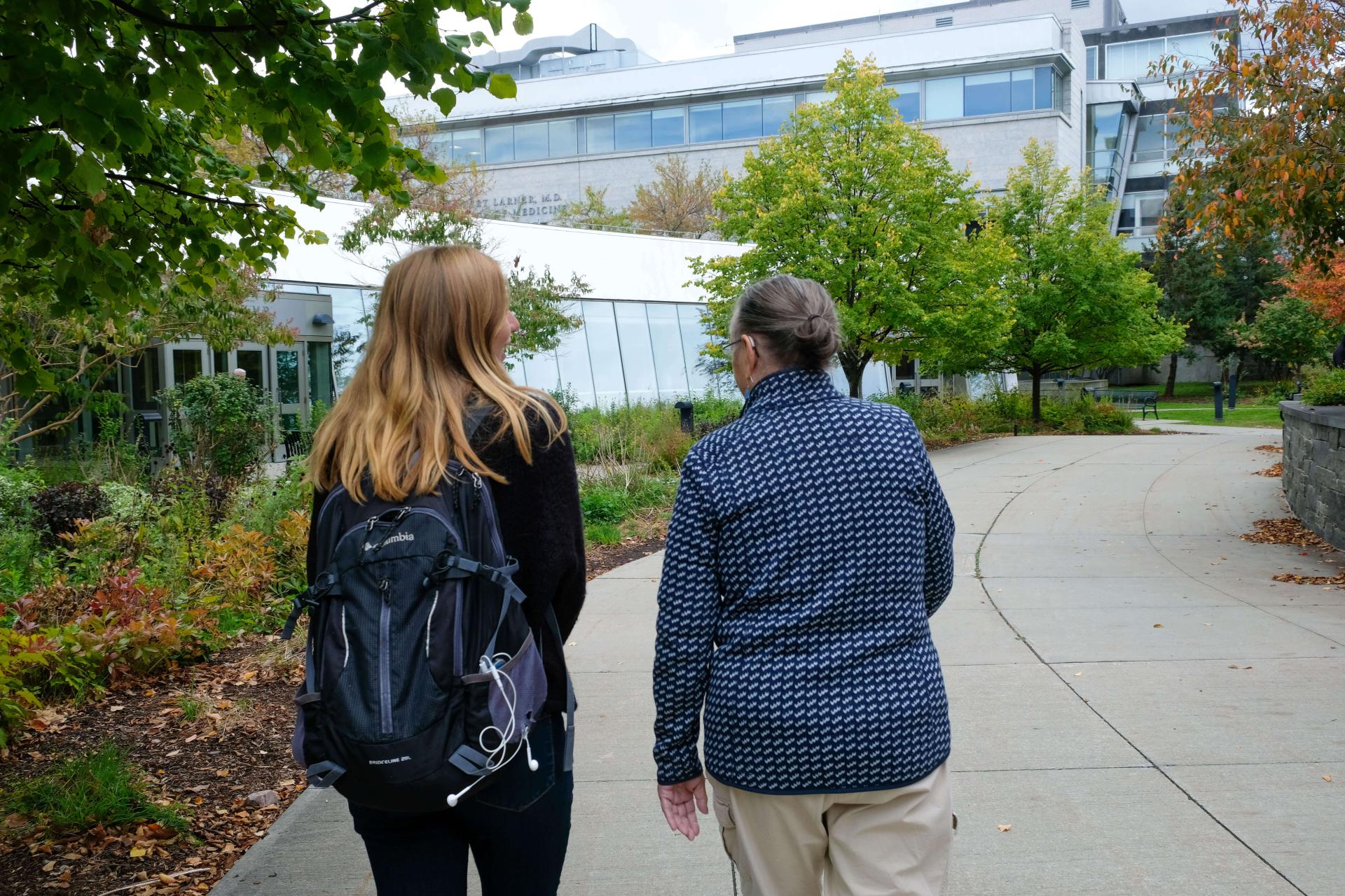 Older adult and student with a backpack walking together