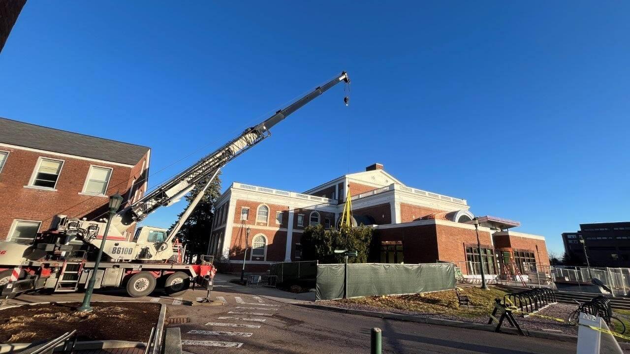 Construction crane lowering new chiller in place on southwest exterior of Fleming Museum