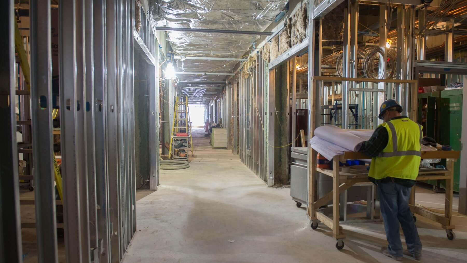 construction worker reading a blueprint interior of building under construction