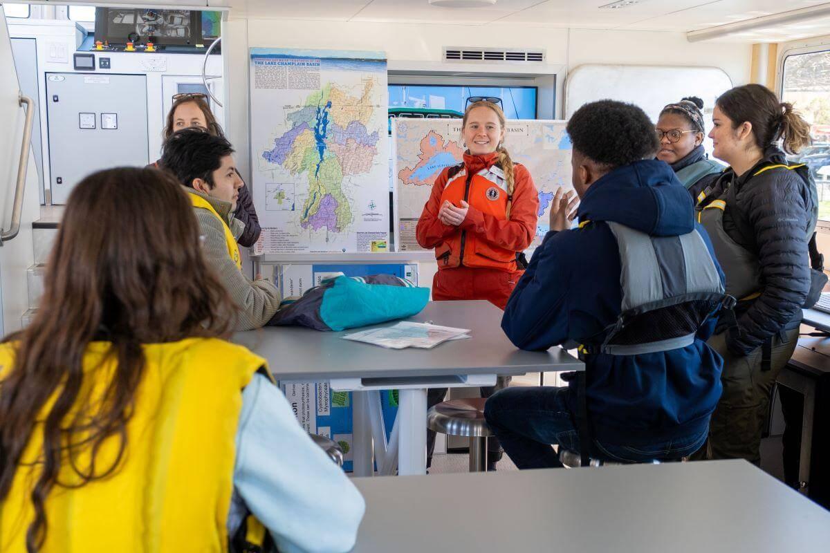 A group of students inside the Marcelle Melosira listening to a presentation in the lab space onboard