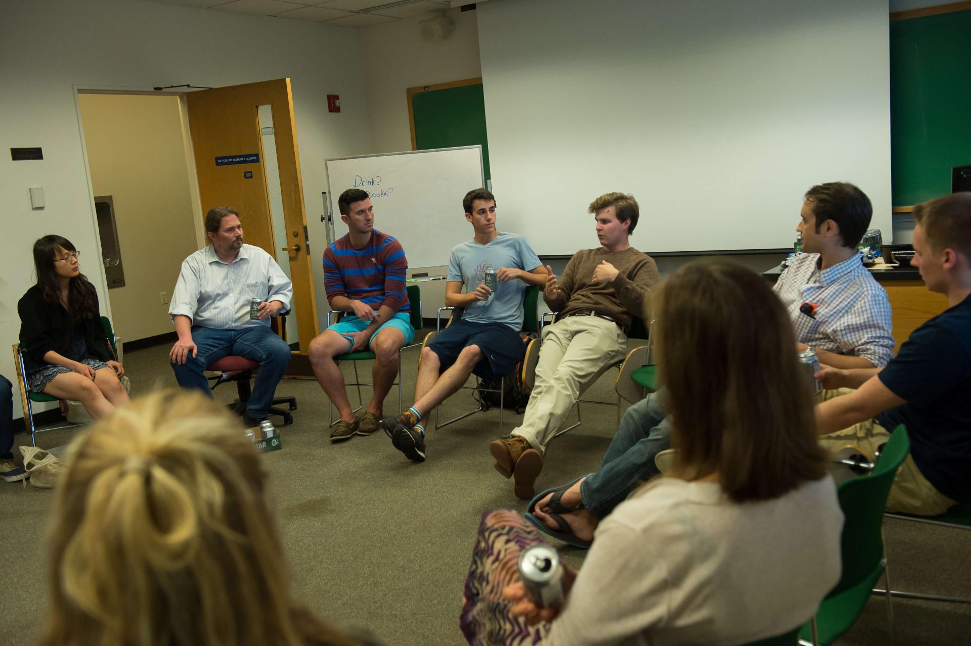 Group of people sitting in a circle in a classroom engaged in conversation