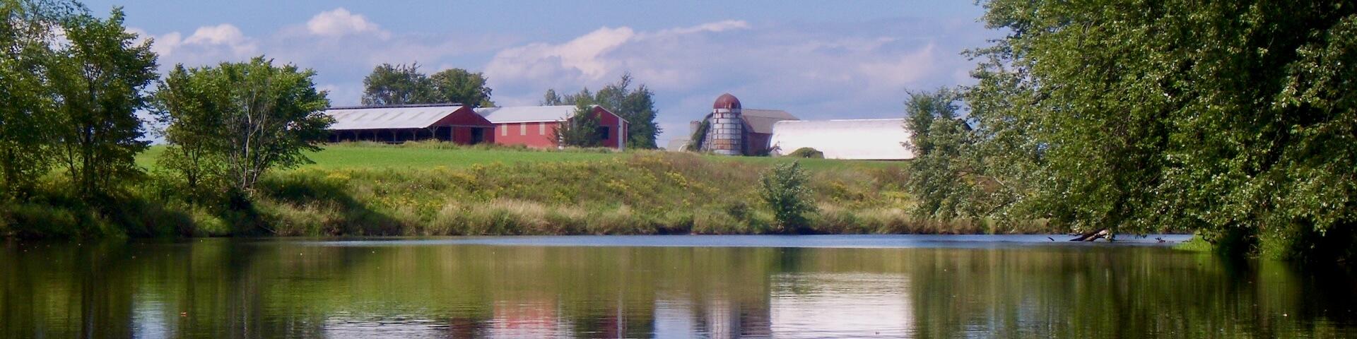 farm buildings near a calm river
