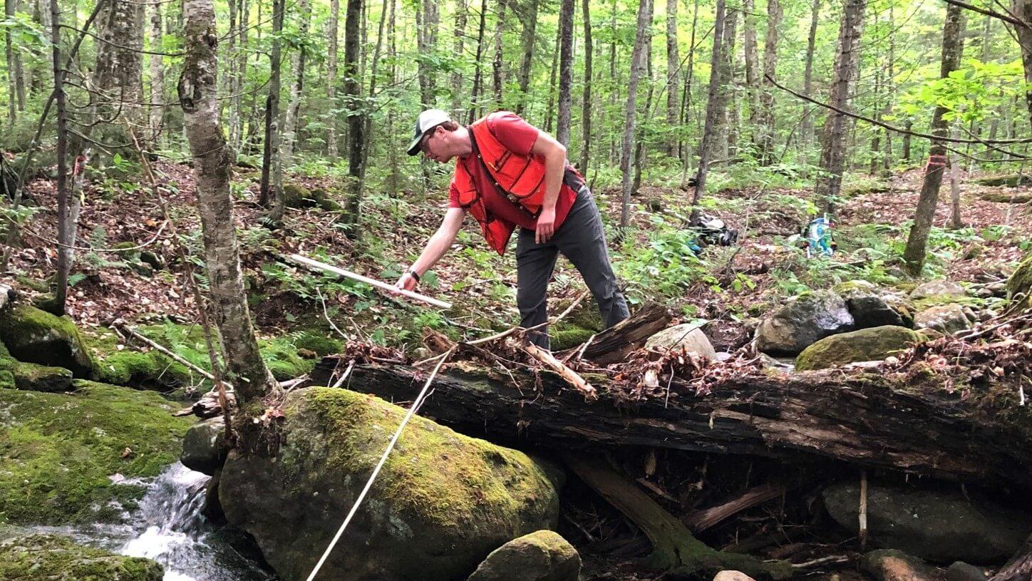 Lead research author Stephen Peters-Collear measures a log in a stream
