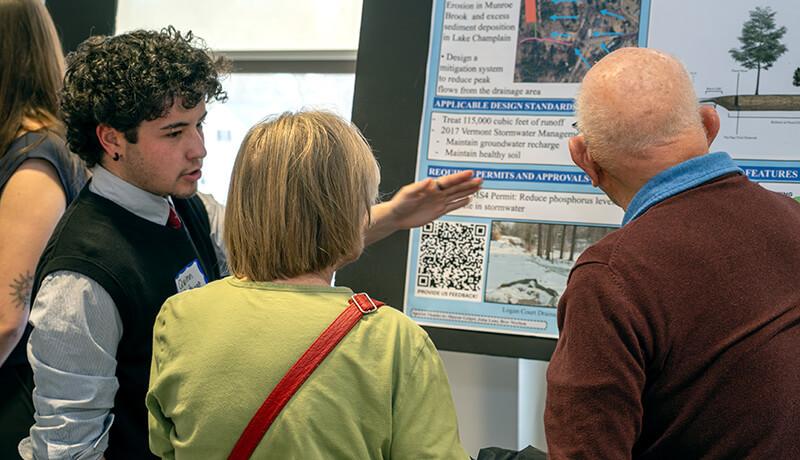 CEE senior Quinn Metzgar shares his team’s project, “Town of Shelburne Logan Court Flow Restoration Stormwater Mitigation,” with visitors during 2025 Engineering Design Night.