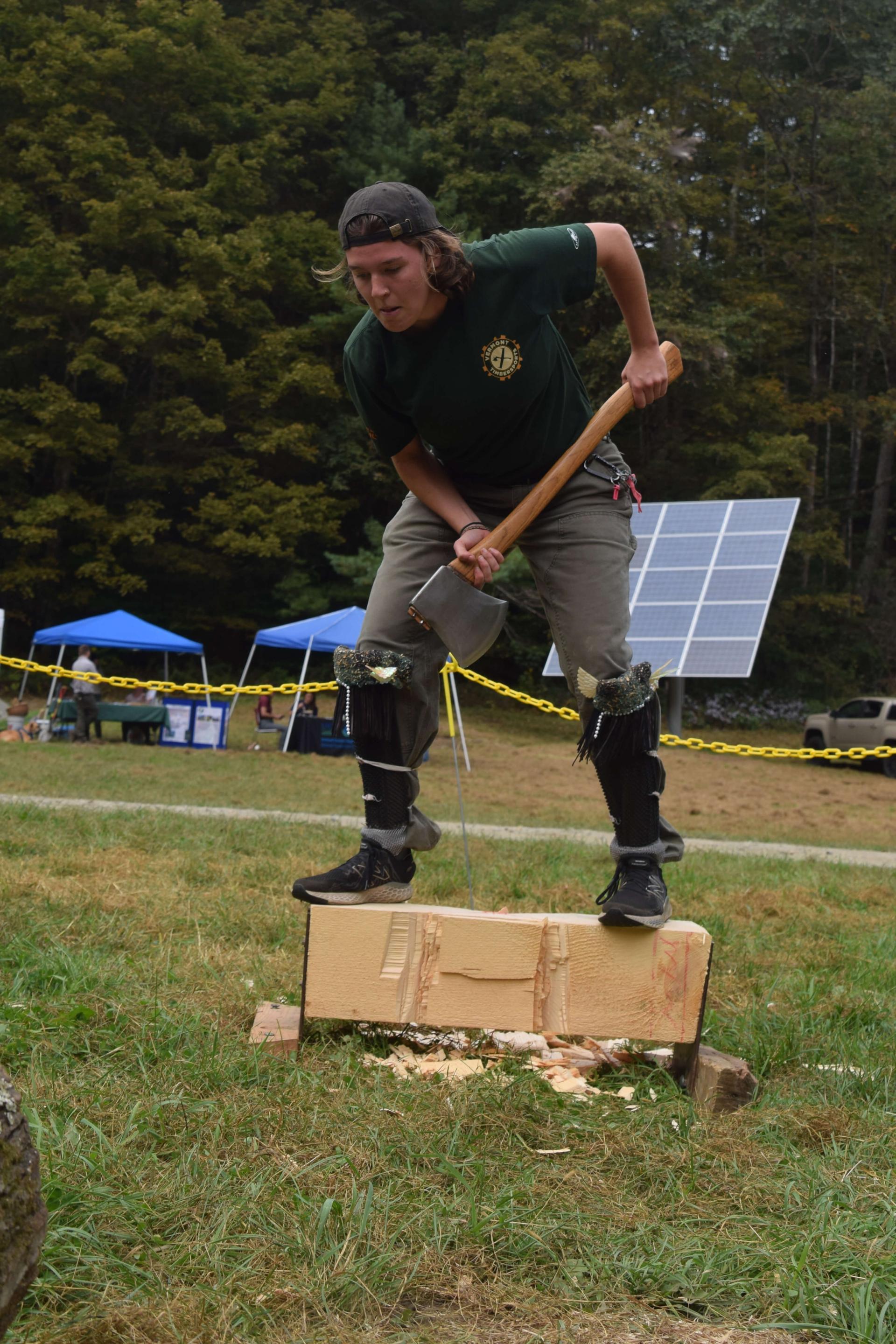 Es Sweeney standing on a piece of cut log holding an axe during a timbersports competition.