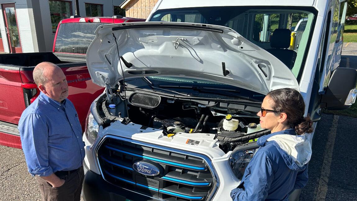 Two people studying an electric vehicle.