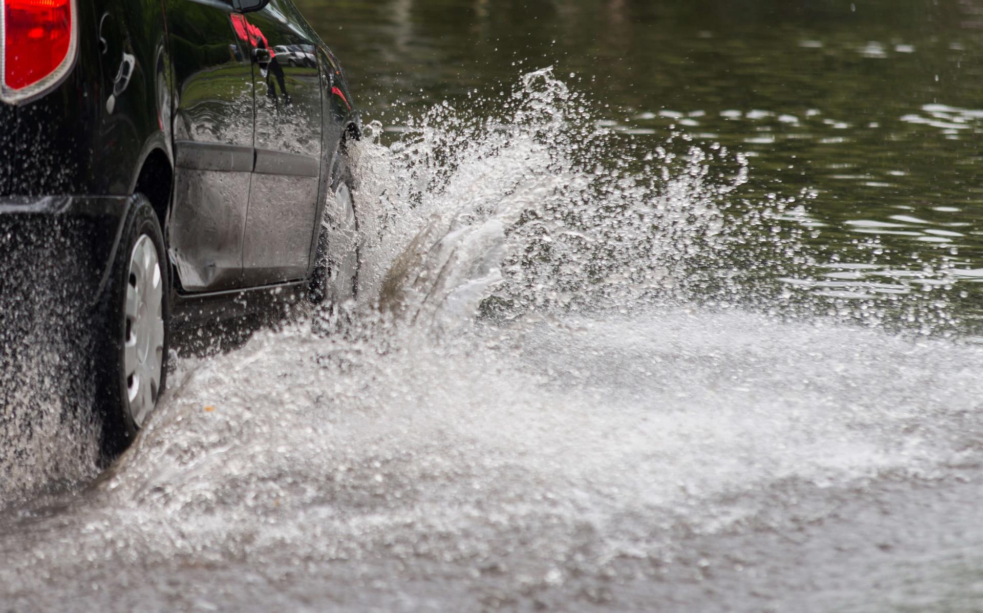 Car driving through a flooded street.