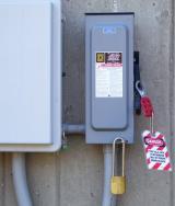 Red and white lockout tagout tag hanging from a utility box